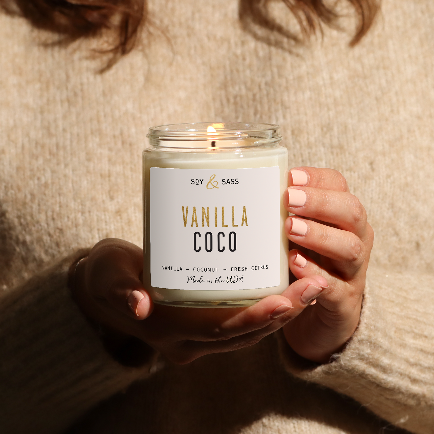 Person holding a 'Vanilla Coco' candle in a warm setting