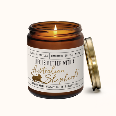 Candle in an amber jar with a label about Australian Shepherds on a white background